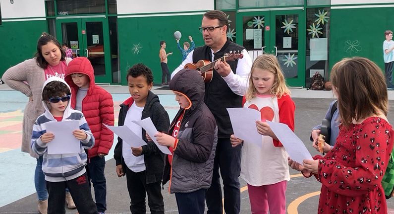 2 adults and several children making music together