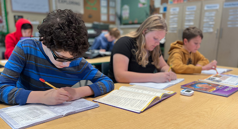 Several children studying at a long table