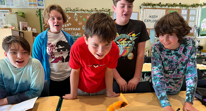 5 boys looking in awe at a small fire in a science experiment